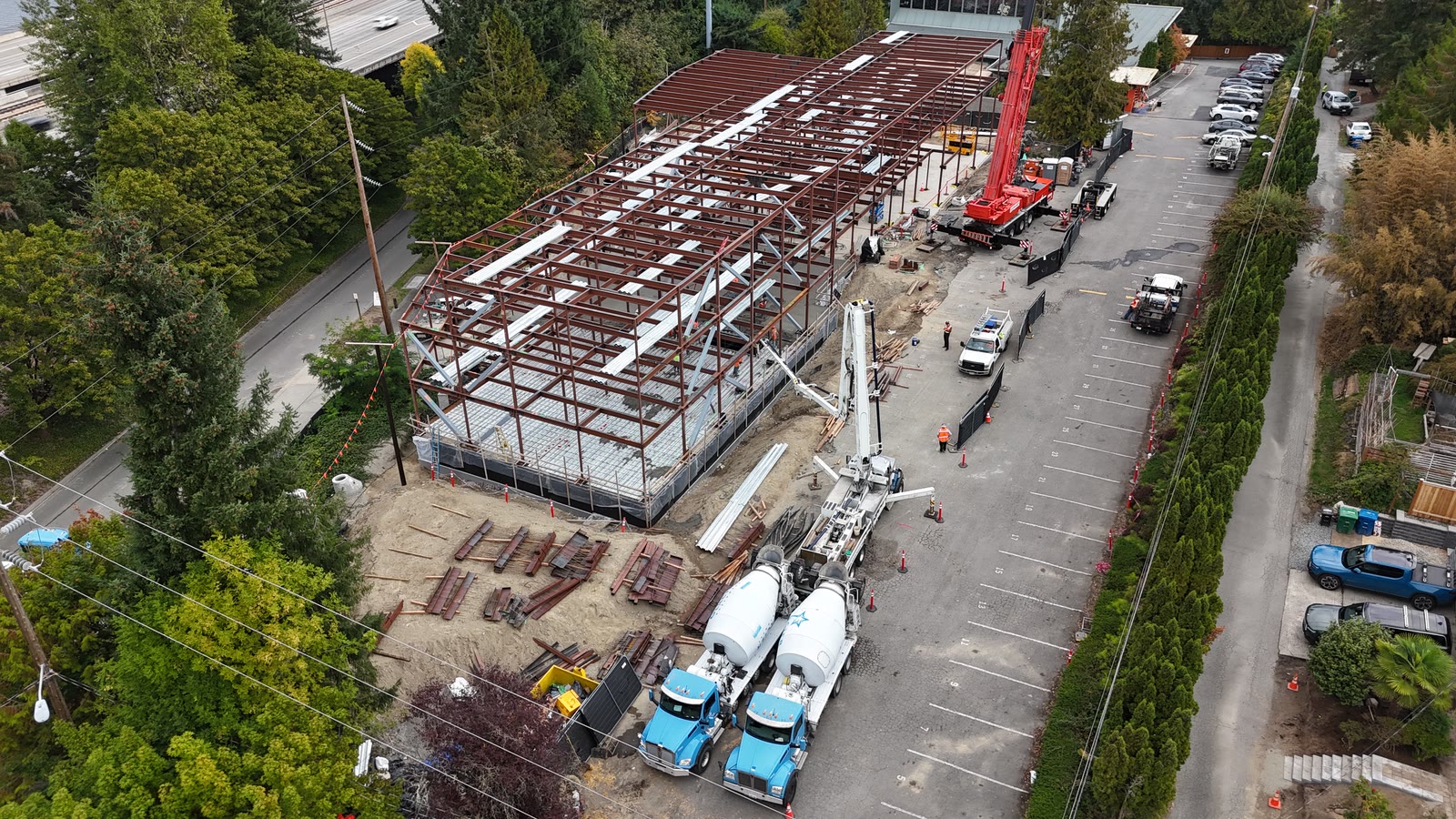 Concrete trucks and boom pump staged alongside the steel frame during the deck pour